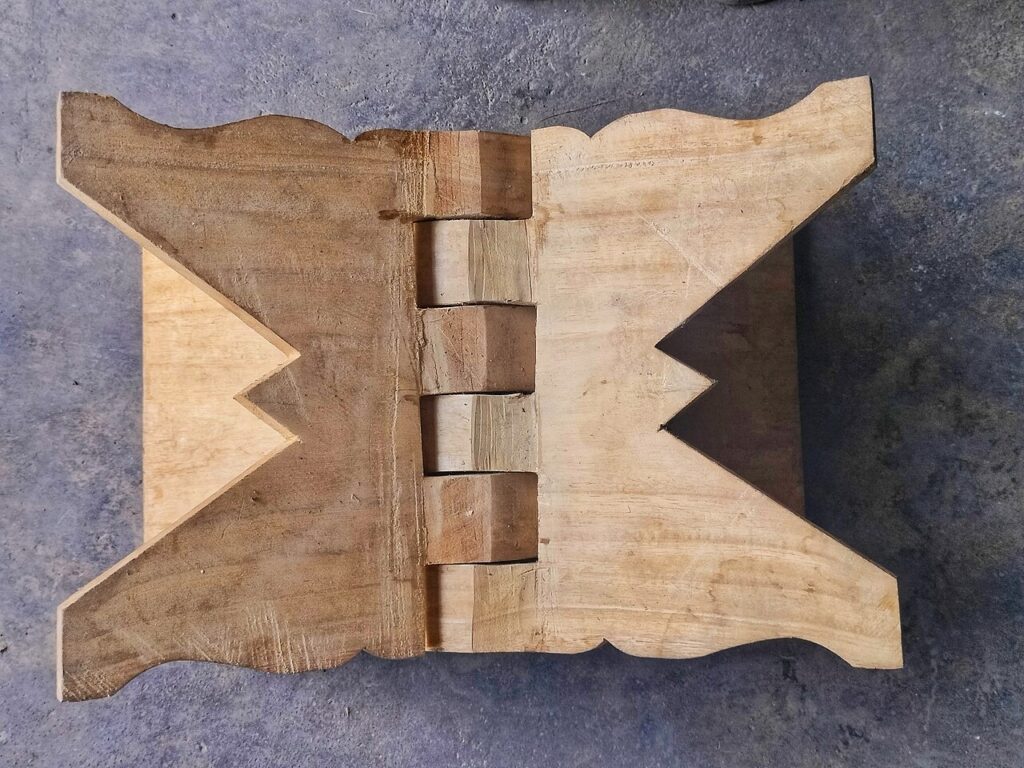 Wooden book stand folded flat, showing interlocking central hinges and shaped side panels.