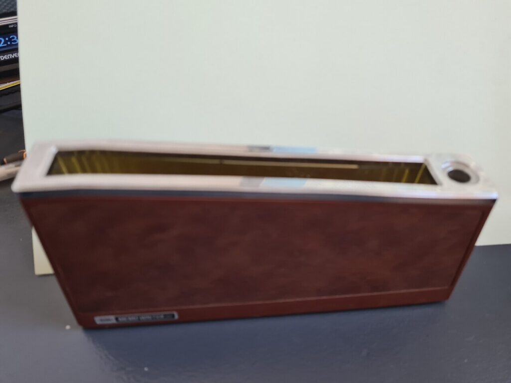 Brown rectangular memo-card holder with a long open slot and a circular pen opening at one end.